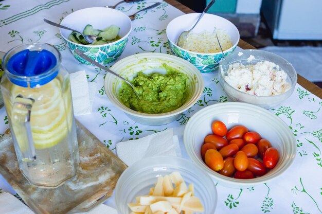 Cuencos sobre la mesa con guacamole tomates cherry queso crema queso y pepino