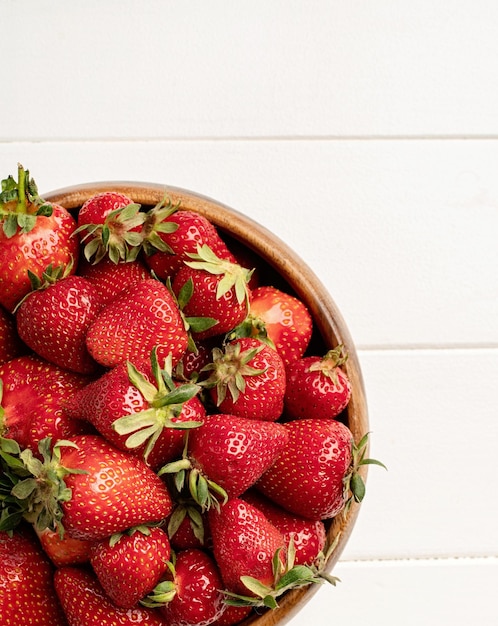 Cuencos de vista superior con fresas orgánicas frescas sobre fondo blanco de madera primer plano