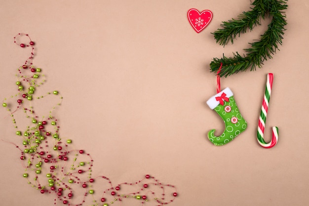 Cuentas festivas de Navidad, una bota rojo-verde para dulces colgando de un fondo de rama de árbol de Navidad