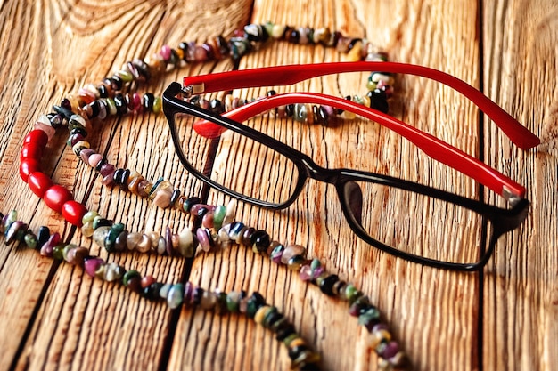 Cuentas de una turmalina multicolor y gafas sobre un fondo de madera