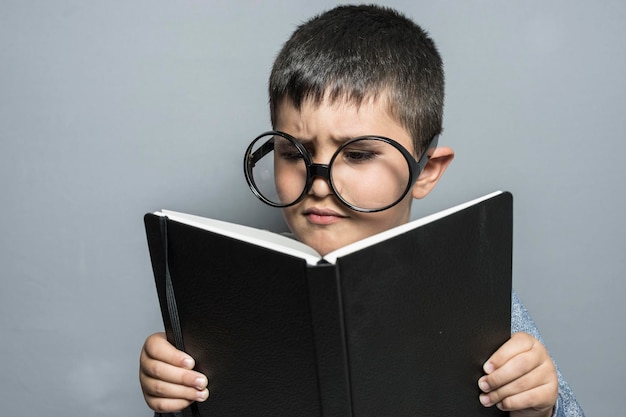 Cuento, Niño con anteojos gigantes leyendo un libro con gestos divertidos y variados