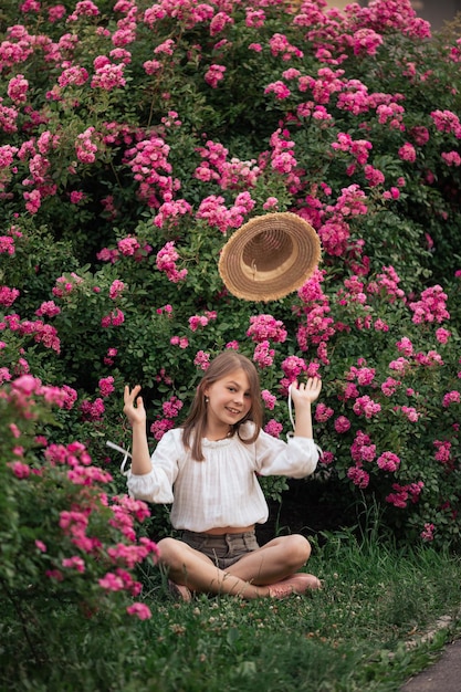 Foto cuentos de verano de una niña camiseta blanca sombrero de paja rosas rosas