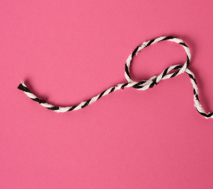 Foto cuerda blanco-negra sobre un fondo rosa enrollado en un lazo