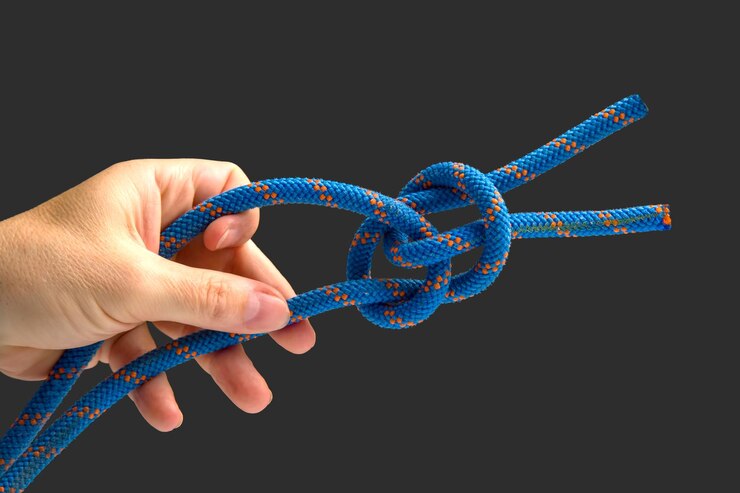 Foto cuerda de color duradera para equipos de escalada en un nudo de fondo oscuro de cable trenzado para turismo y viajes
