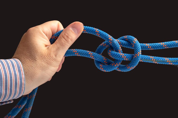 Foto cuerda de color duradera para equipos de escalada en un nudo de fondo oscuro de cable trenzado para turismo y viajes