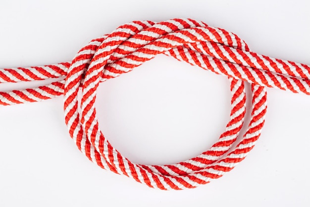 Cuerda roja en un nudo aislado sobre fondo blanco.
