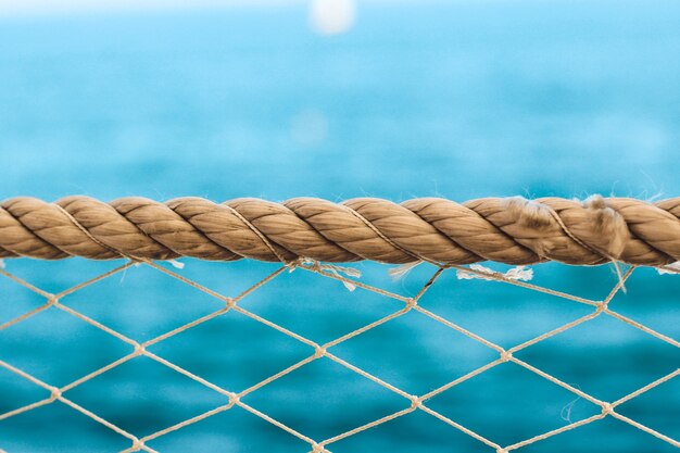 Cuerda de textura náutica y malla con barco en el fondo del agua de mar.