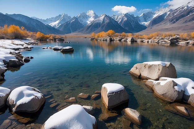 Un cuerpo de agua con nieve sobre rocas y montañas al fondo