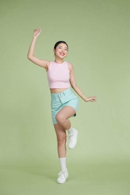 Foto cuerpo completo de chica feliz bailando tus manos sobre fondo verde pastel