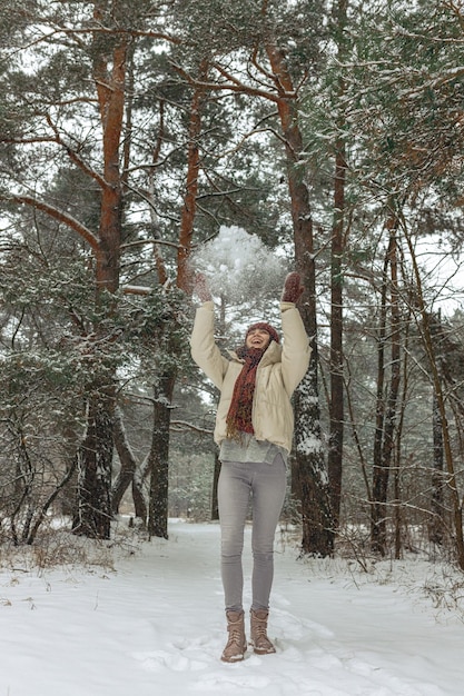 Cuerpo completo de mujer feliz con ropa de abrigo tirando nieve y expresando alegría