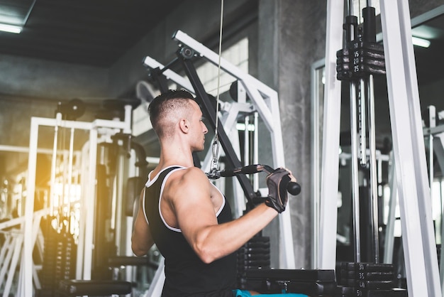 Cuerpo en forma cruzada y musculoso en el gimnasio. Hombre fuerte y guapo haciendo ejercicios de entrenamiento.