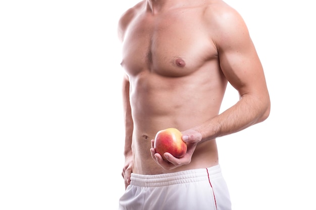 Cuerpo de un joven atlético masculino caucásico desnudo hasta la cintura aislado en fondo blanco con una manzana en la mano