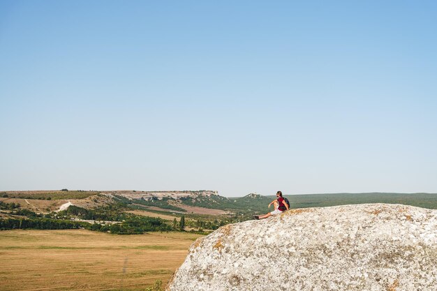 Foto cuerpo lleno de viajero masculino de pie en una montaña rocosa en un día de verano