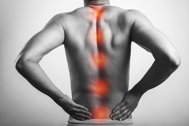 El cuerpo masculino sin camisa dolor en la anatomía de la médula espinal con marca roja en la columna vertebral