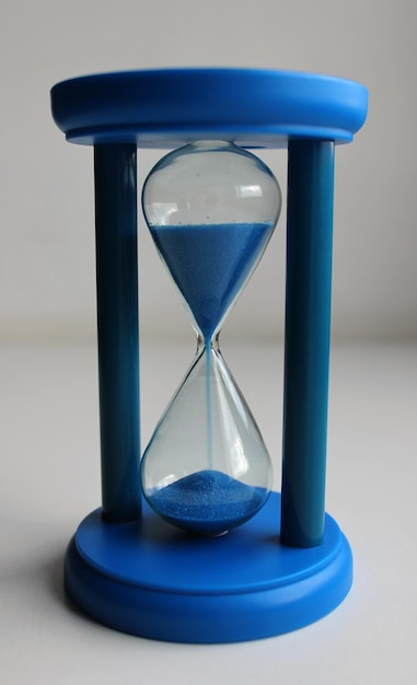 Cuerpo de plástico de un reloj de tiempo de vidrio con arena azul que se vierte en el interior
