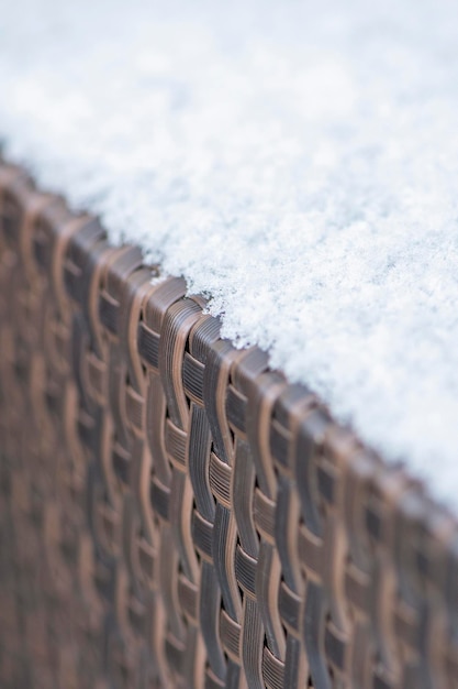 Cuidado y almacenamiento de muebles de jardín en invierno textura de mobiliario urbano en invierno Rattan artificial cubierto de nieve closeup