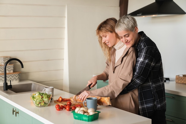 Cuidado y amor Lesbianas tiernas abrazándose abrazándose en la cocina cocinando y cortando verduras juntos teniendo una cita romántica relación LGBT amor confiable de dos amigas jóvenes