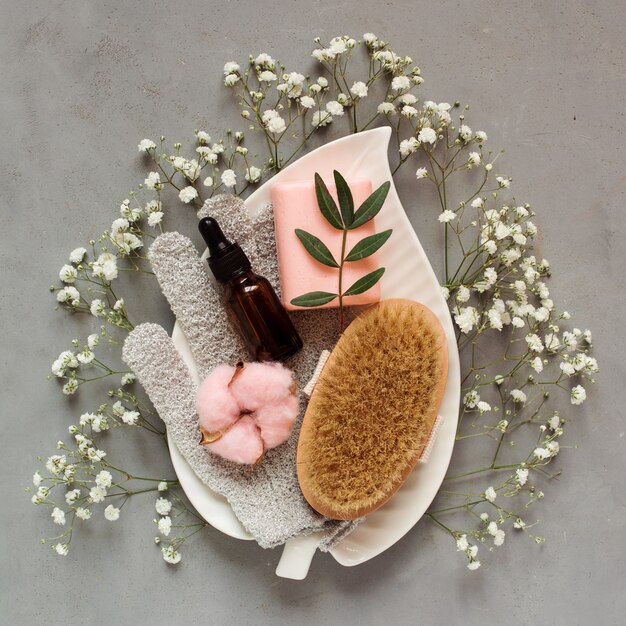 Cuidado de la belleza en el plato blanco entre flores blancas sobre fondo gris, accesorios para el tratamiento de la piel.