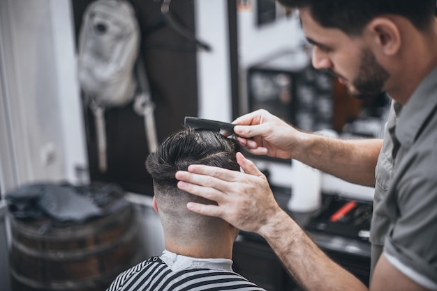 Cuidado del cabello. Barbero hace un corte de pelo con tijeras. Enfoque suave.