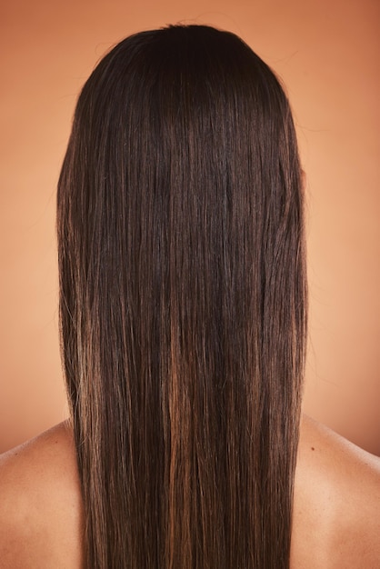 Cuidado del cabello de belleza y mujer con un balayage en un estudio desde atrás con un hermoso peinado Bienestar natural y modelo con un estilo de cabello largo y limpio aislado por un fondo naranja