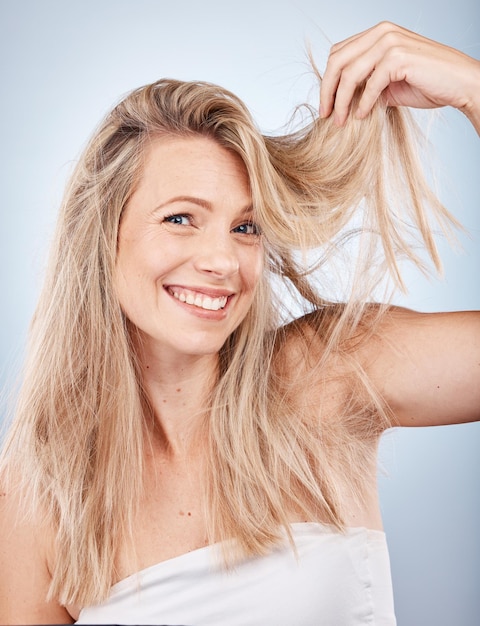 Cuidado del cabello de belleza y retrato de mujer en estudio sobre fondo gris Textura de cabello de peinado y modelo femenino con cabello rubio saludable y largo después de cosméticos o tratamiento de cabello de salón para el crecimiento