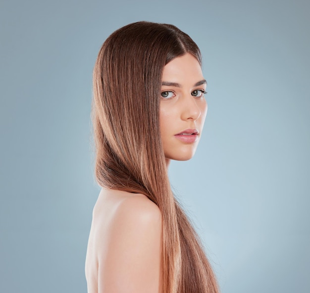 El cuidado del cabello es importante. Foto de estudio de una hermosa joven mostrando su largo cabello castaño.