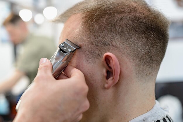 Cuidado del cabello masculino. Corte de pelo en peluquería. El peluquero hace un hermoso peinado para el cliente.