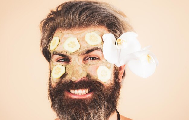 Cuidado de la cara del hombre de primer plano Hombre divertido con crema facial con pepino