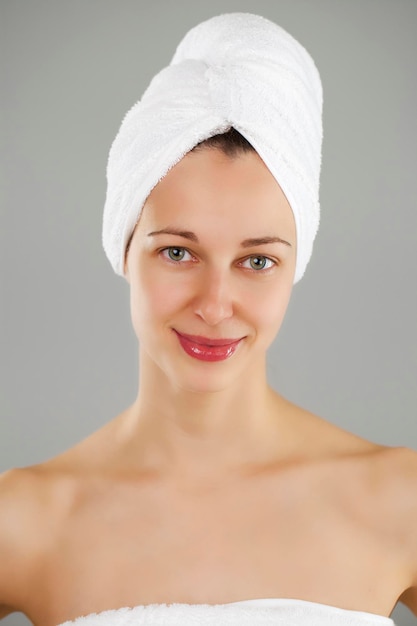 Cuidado del cuerpo Mujer joven hermosa posando en una toalla blanca Cuidado de la salud de Spa aislado en fondo gris