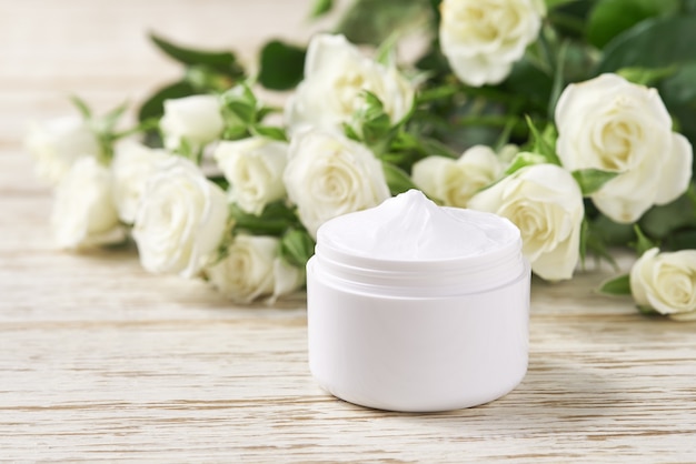 Cuidado de rosto luxuoso e conceito de creme orgânico. Creme hidratante para peles sensíveis, cosmético de spa e produto de limpeza natural para a pele em um fundo de rosas brancas.