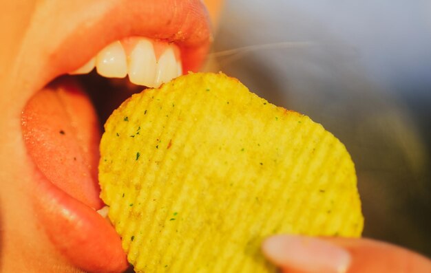 Cuidado dental boca de chica de primer plano con placer come papas fritas