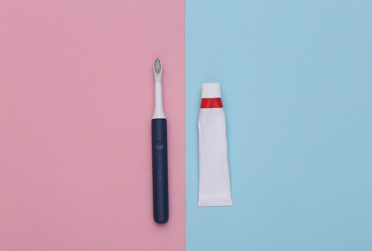 Foto cuidado dental. tubo de pasta de dientes con cepillo de dientes sobre fondo rosa azul.