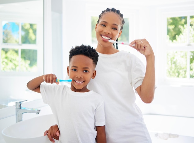 El cuidado de los dientes y las encías es crucial para la salud a largo plazo. Retrato de niño y su madre cepillándose los dientes juntos en un baño en casa.