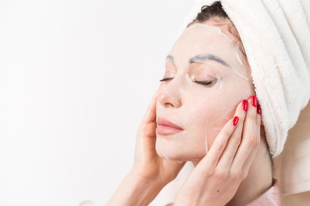 Cuidado facial y tratamientos de belleza Mujer con una mascarilla hidratante en la cara aislada sobre fondo blanco
