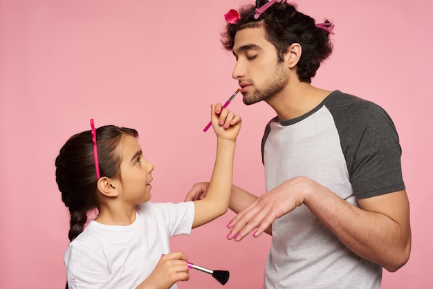 Foto cuidado família árabe. menina faz maquiagem para o pai.