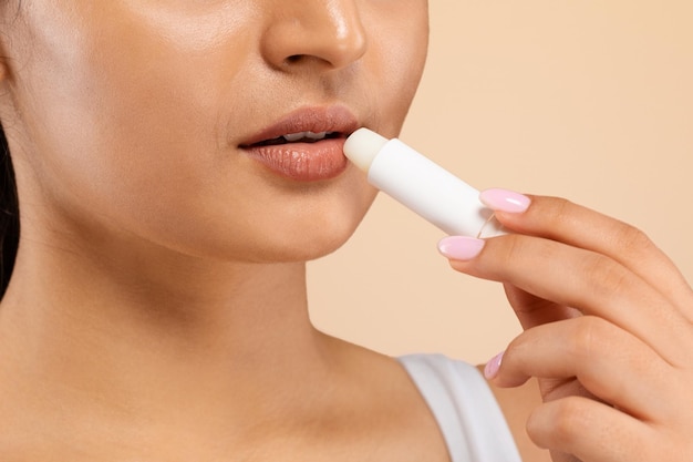 Cuidado de los labios mujer india usando lápiz labial para hidratar sus hermosos labios regordetes