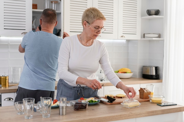 El cuidado del marido ayuda a la esposa mayor amorosa con la cena pareja romántica ancianos cocinar el desayuno en