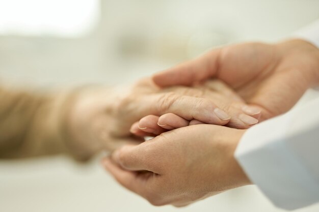 Cuidado médico sosteniendo y examinando la mano de un paciente mayor