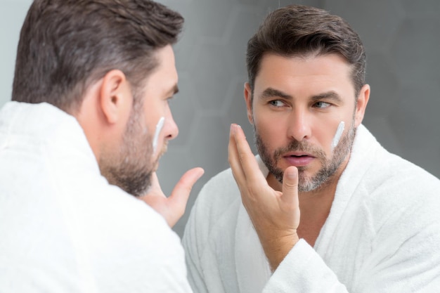 Cuidado de la piel belleza hombre de mediana edad aplicar crema facial spa masculino mantener crema facial crema facial hidratante