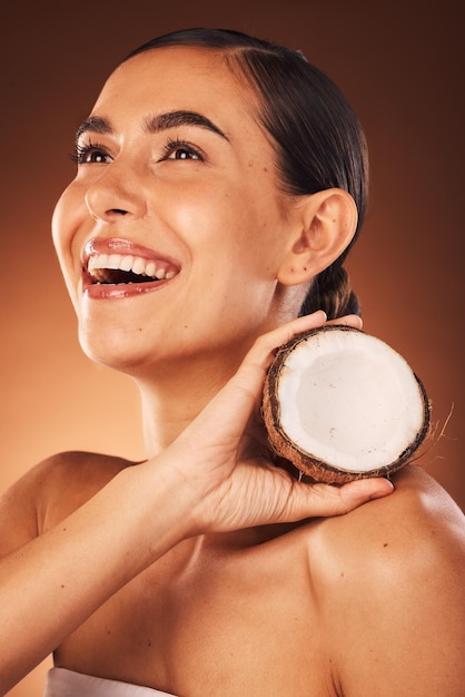 Foto cuidado de la piel coco y mujer en el estudio felices de promover la dieta de frutas beneficia los cosméticos de belleza o el tratamiento facial sonrisa mujer joven o saludable comercializando o publicitando aceite de coco para una cara brillante