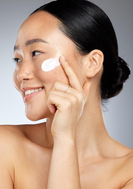 Cuidado de la piel coreano feliz y crema facial para la piel de una mujer con una sonrisa usando loción Felicidad de una persona de Corea sonriendo sobre el bienestar facial belleza cuidado cosmético y crema hidratante de suero dermatológico