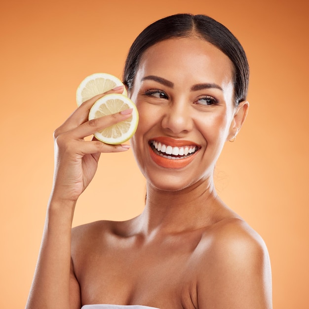 Cuidado de la piel facial y mujer con limón para la salud, el bienestar y la vitalidad en el fondo del estudio naranja Sonrisa modelo y mujer de Canadá con cítricos para minerales saludables de vitamina c o nutrición