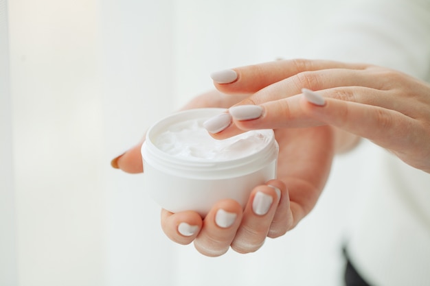 Foto cuidado de la piel de las manos. cerca de manos femeninas con tubo de crema, manos de mujer hermosa con uñas de manicura natural aplicando crema cosmética para manos sobre piel suave, sedosa y saludable