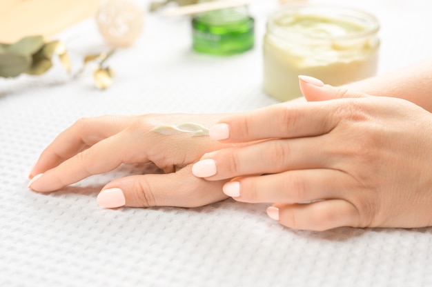 Cuidado de la piel de las manos. Primer plano de hermosas manos femeninas con uñas de manicura natural. Cerca de la mano de la mujer aplicando crema hidratante sobre su suave piel sedosa y saludable. Belleza y salud. enfoque selectivo