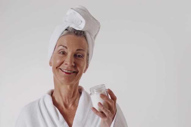 Cuidado de la piel mujer caucásica madura alegre sonriendo aplicando crema hidratante en loción o máscara facial