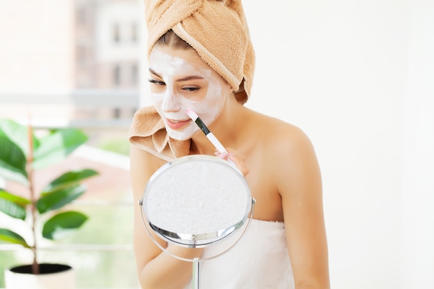 Cuidado de la piel, mujer joven con hermosa piel facial aplicar mascarilla en la cara