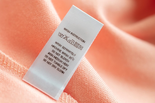 Cuidado de la ropa blanca instrucciones de lavado etiqueta de ropa en camisa de algodón rosa