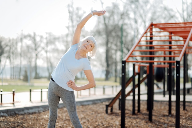 Cuidado de la salud. Alerta anciana vistiendo ropa deportiva y haciendo ejercicio al aire libre