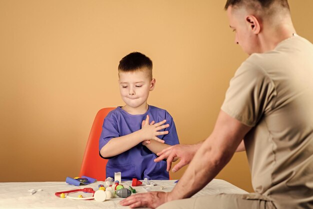 Cuidado de la salud concepto de pediatra examen médico niño lindo y su padre médico trabajador del hospital servicio médico laboratorio de análisis niño pequeño médico sentarse en la mesa herramientas médicas