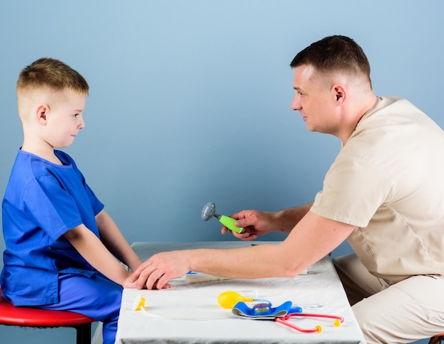 Cuidado de la salud Cuidado de niños Pediatra cuidadoso verificar la salud del niño Examen médico Servicio médico Hombre médico sentarse mesa herramientas médicas examinar niño pequeño paciente Concepto de pediatra